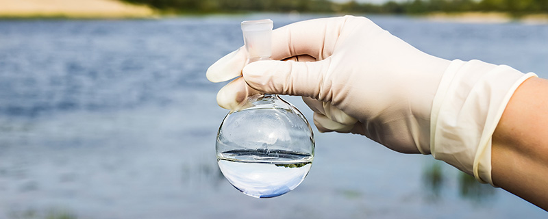 Clean Water Act Banner Hand holding water test tube with lake in the background