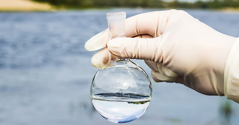 White glove hand holding test tude with clear water
