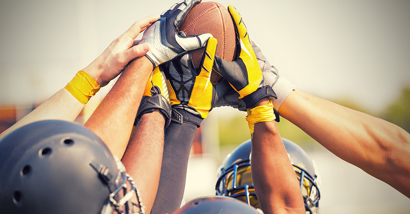 Football players huddle around football