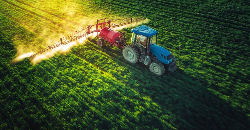 Red tractor spraying crops