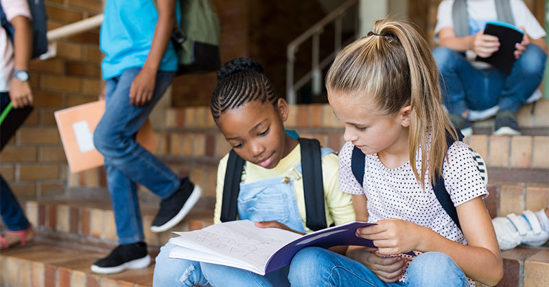 Specialty Human Services - Boys & Girls Club Two young girls on school steps looking at a notebook